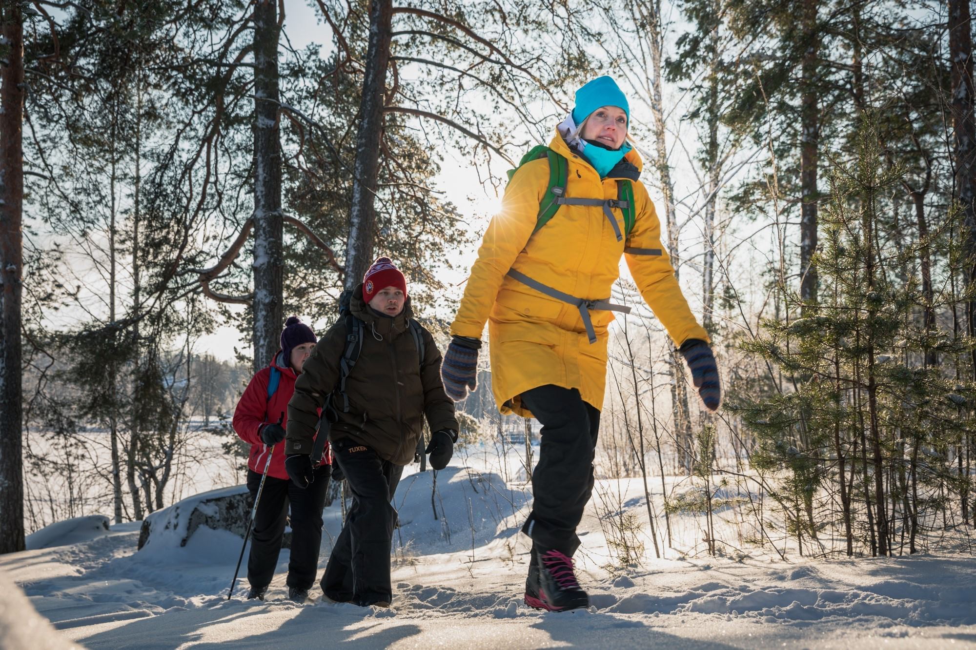 Liikuntapalvelupäällikkö Anna Seppänen ulkoilemassa  lumisessa metsässä kahden muun henkilön kanssa
